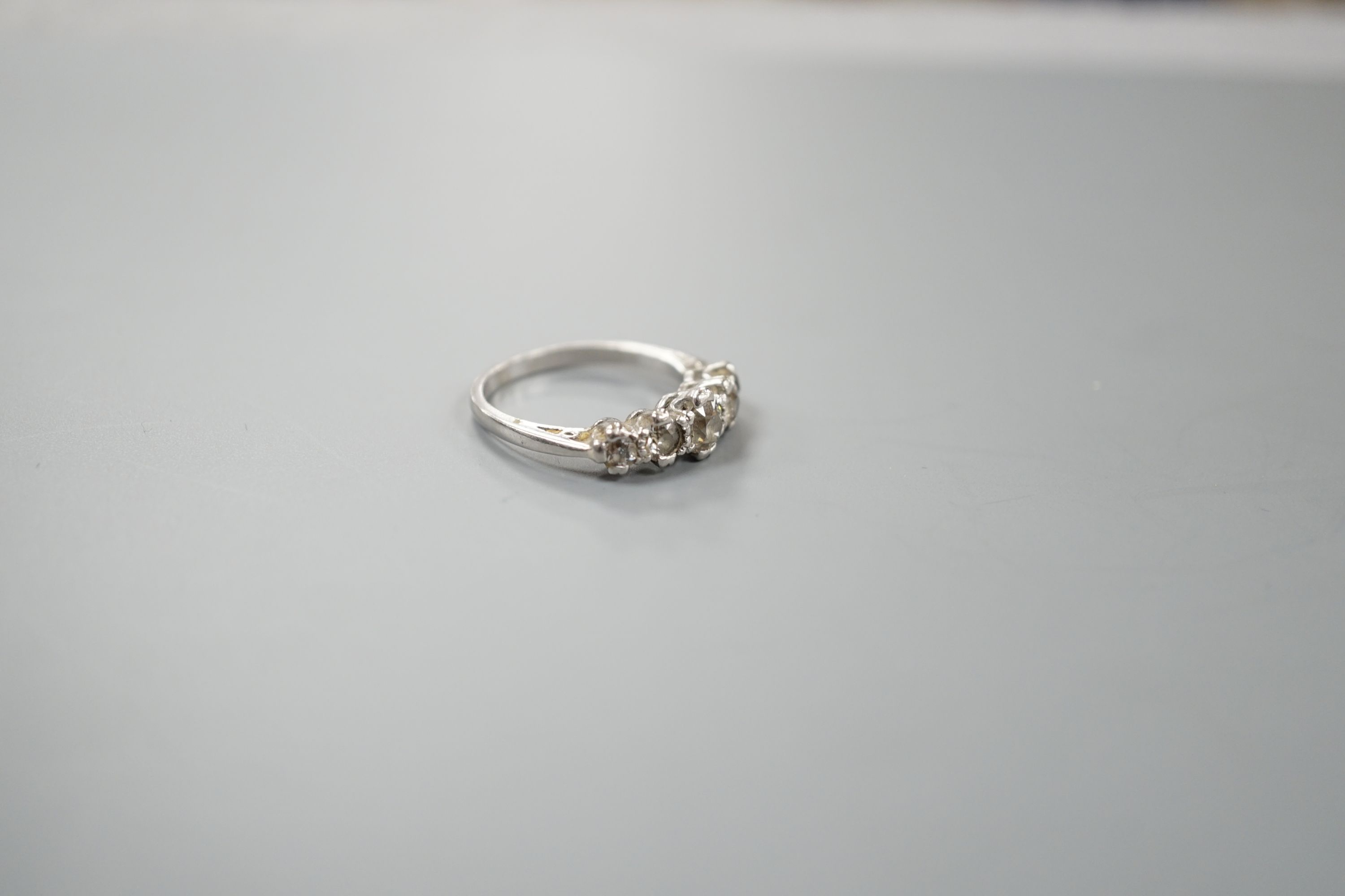 A modern platinum and graduated five stone diamond set half hoop ring, size P/Q, gross weight 6 grams.